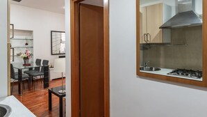 Une cuisine moderne équipée d’une hotte en acier inoxydable, d’un évier et d’une cuisinière. On y trouve également un coin repas avec une table et des chaises en verre.