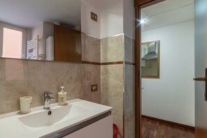 A bathroom with a white sink, a mirror, and a shower area.