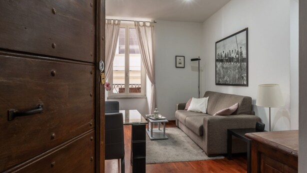 Ein Wohnzimmer mit einer Couch, einem Couchtisch, einer Lampe und einem Holzkabinett.