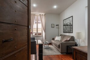 Un salon comprenant un canapé, une table basse, une lampe et un meuble en bois.