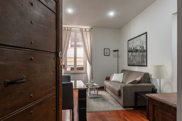 A living room with a sofa, a coffee table, a lamp, and a wooden cabinet.