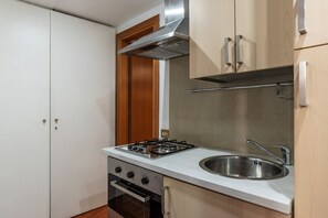 A compact kitchen with a gas stove, oven, and stainless steel sink.