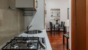 Une cuisine compacte équipée d’une cuisinière à gaz, d’un évier et d’un coin repas avec des chaises et une table.