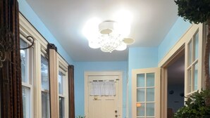 Ein Flur mit Holzboden, einem grünen Sofa, einer Kübelpflanze und einer Tür mit geätzten Glasscheiben.