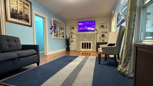 Ein Wohnzimmer mit Kamin, Fernseher und einem blau-grauen Streifen Teppich.