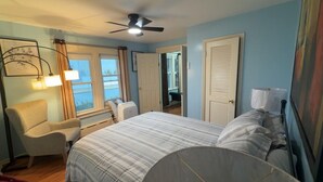 Ein Schlafzimmer mit Bett, Stuhl, Deckenventilator und Fenster.