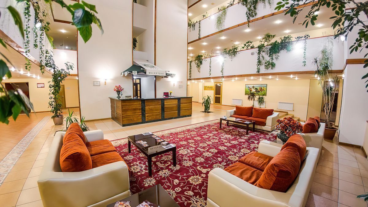 A spacious lobby with a reception desk, seating area, and multiple levels with plants.