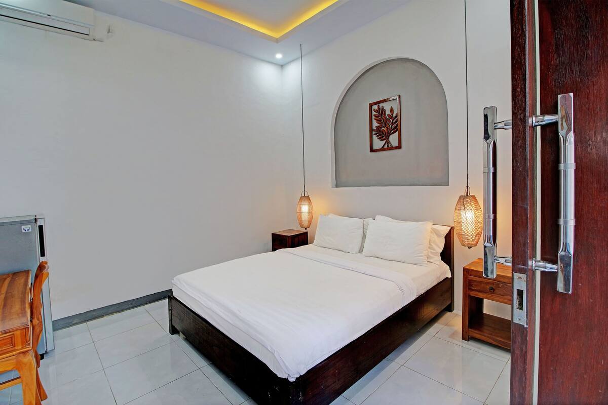 A neatly arranged bedroom with a bed, bedside tables, a desk, and a chair.