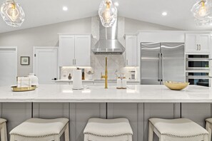 Una cocina moderna con armarios blancos, electrodomésticos de acero inoxidable y encimera de mármol.