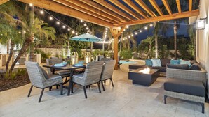 An outdoor patio with a wooden pergola, string lights, a pool table, and outdoor furniture. - Elegant Renovated Home W/ Backyard Misters & Pool (Phoenix)