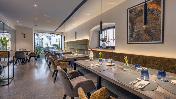 A modern dining area with long tables, comfortable chairs, and pendant lighting. - Nepomuk (Vipiteno)