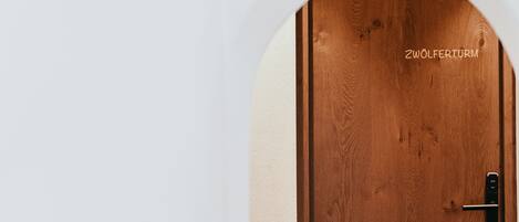 A wooden door with the inscription "ZWÖLFERTURM" and a modern door handle.