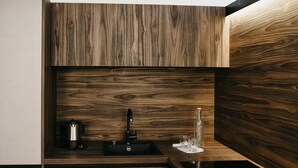 A modern kitchen with a built-in sink, a kettle, and a glass bottle on the countertop. - Nepomuk (Vipiteno)