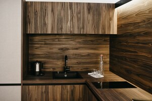 A modern kitchen with a built-in sink, a kettle, and a glass bottle on the countertop.