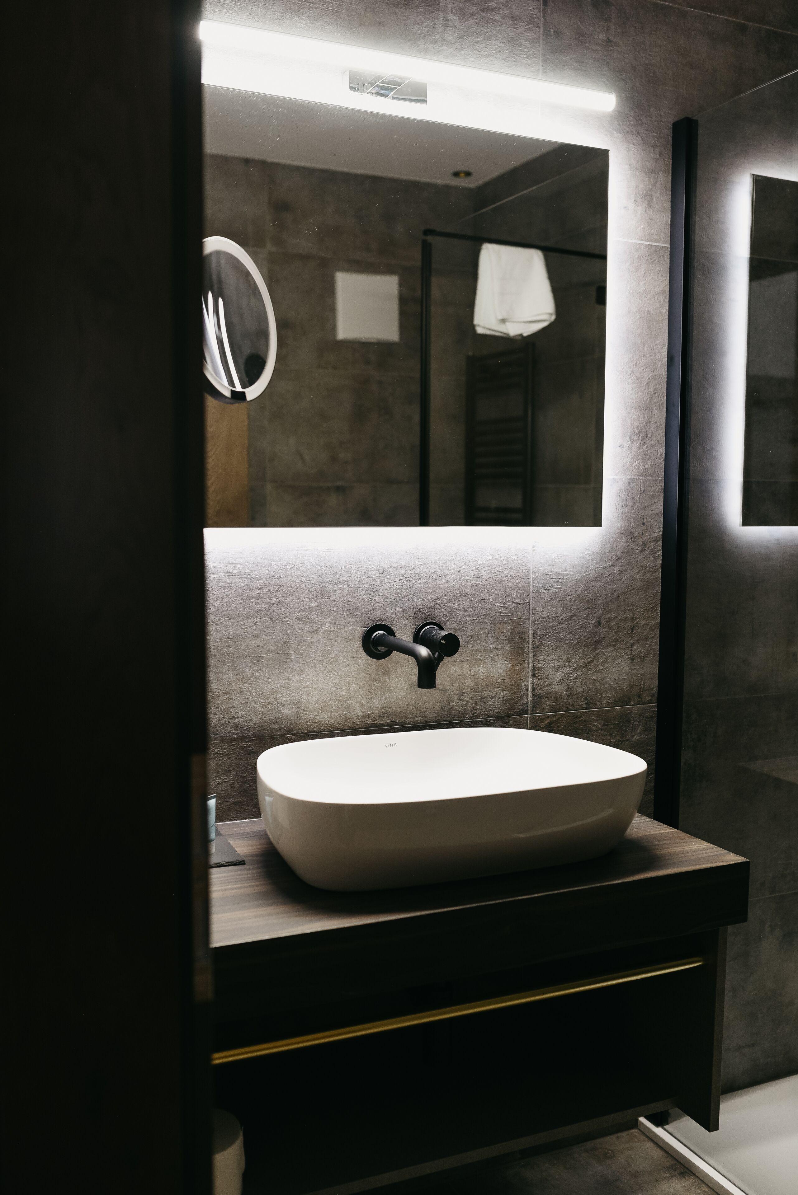 A modern bathroom with a large mirror, a vessel sink, and a towel hanging on a rack.