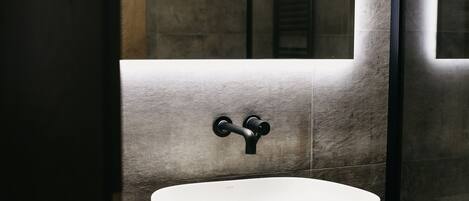 A modern bathroom with a large mirror, a vessel sink, and a towel hanging on a rack.