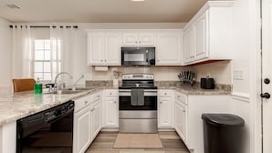 A kitchen with white cabinets, a stainless steel oven, a microwave, and a dishwasher. - Comfortable 3BR | Screened Patio + Grill | WR (Warner Robins)
