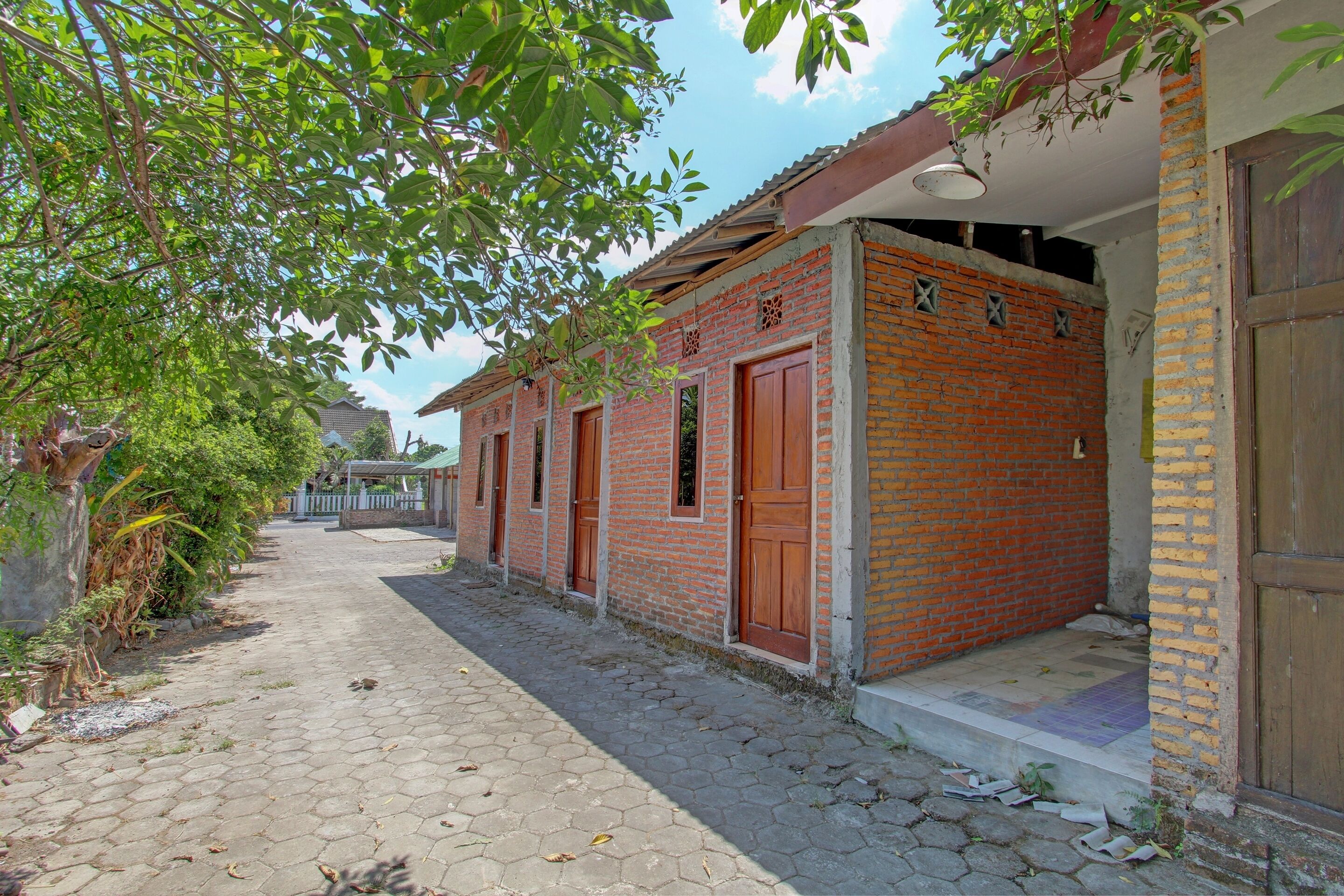 A narrow brick pathway leading to a row of brick buildings with wooden doors and windows.