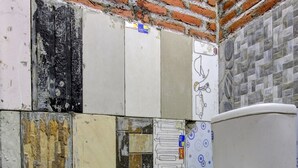 Une salle de bain avec des toilettes, des murs carrelés et un tuyau bleu.
