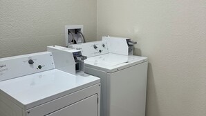A laundry room with two front-loading washing machines and a dryer. - Red Roof Inn Charleston - Dunbar (Dunbar)