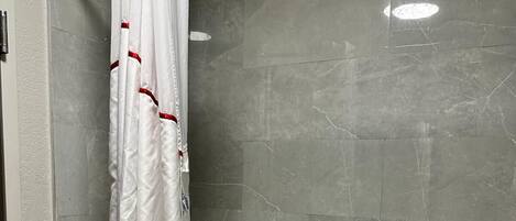 Un baño con bañera, cortina de ducha y baldosas de mármol gris.