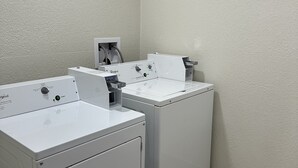 A laundry room with two front-loading washing machines and a dryer. - Red Roof Inn Charleston - Dunbar (Dunbar)