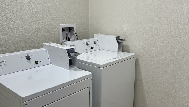 A laundry room with two front-loading washing machines and a dryer. - Red Roof Inn Charleston - Dunbar (Dunbar)