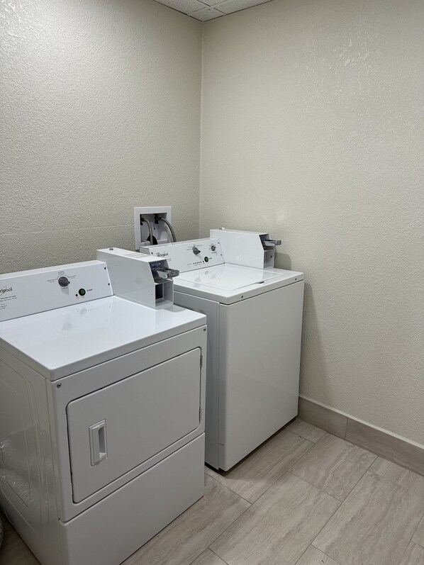A laundry room with two front-loading washing machines and a dryer. - Red Roof Inn Charleston - Dunbar (Dunbar)