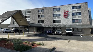 A Red Roof Inn with a modern architectural design, featuring a textured facade and a prominent red sign. - Red Roof Inn Charleston - Dunbar (Dunbar)