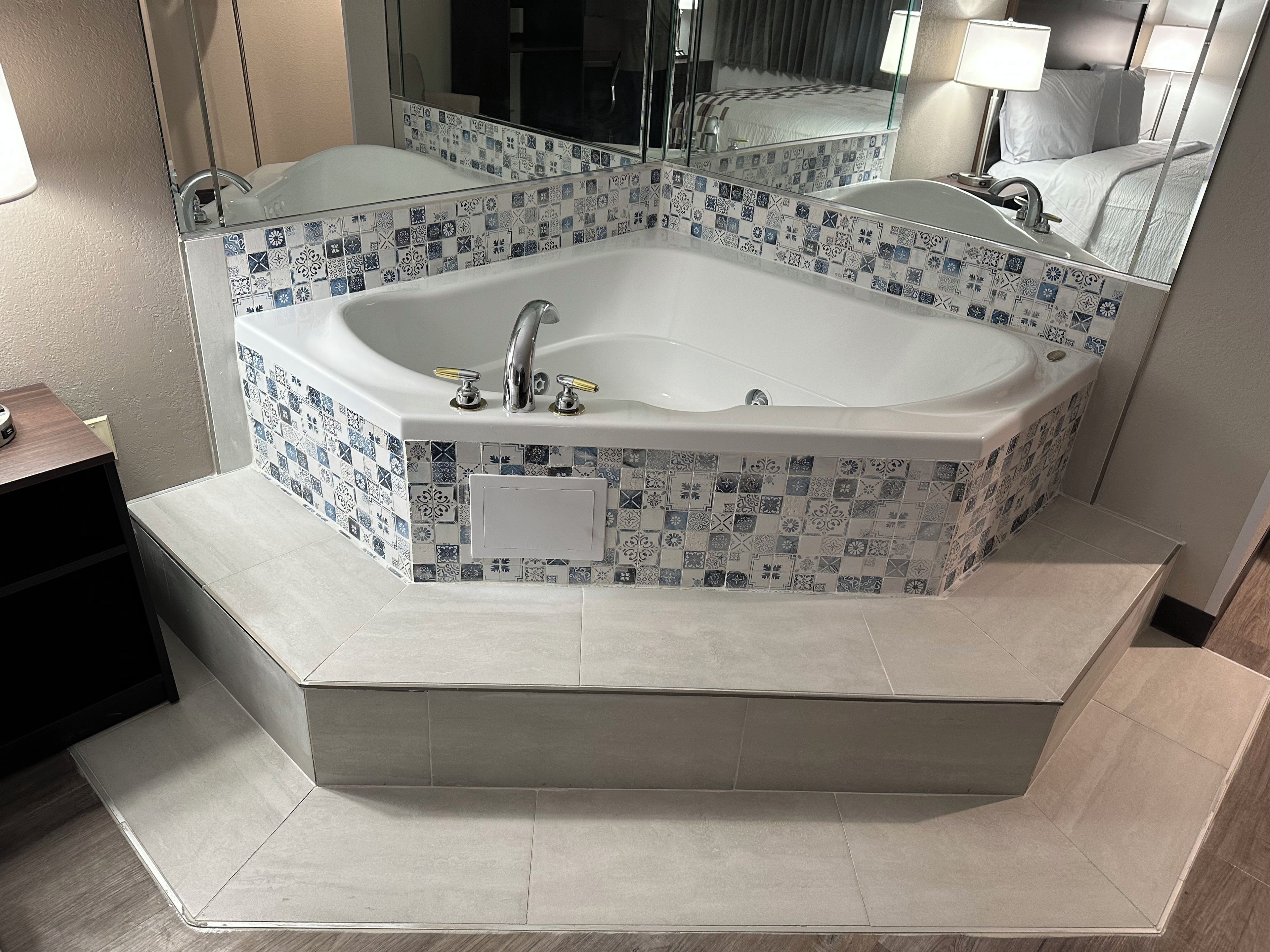 A modern bathroom with a freestanding bathtub, a mirror, and a tiled floor.