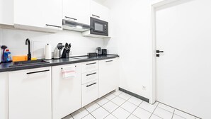 A modern kitchen with white cabinets, a black countertop, a microwave, and a coffee maker.
