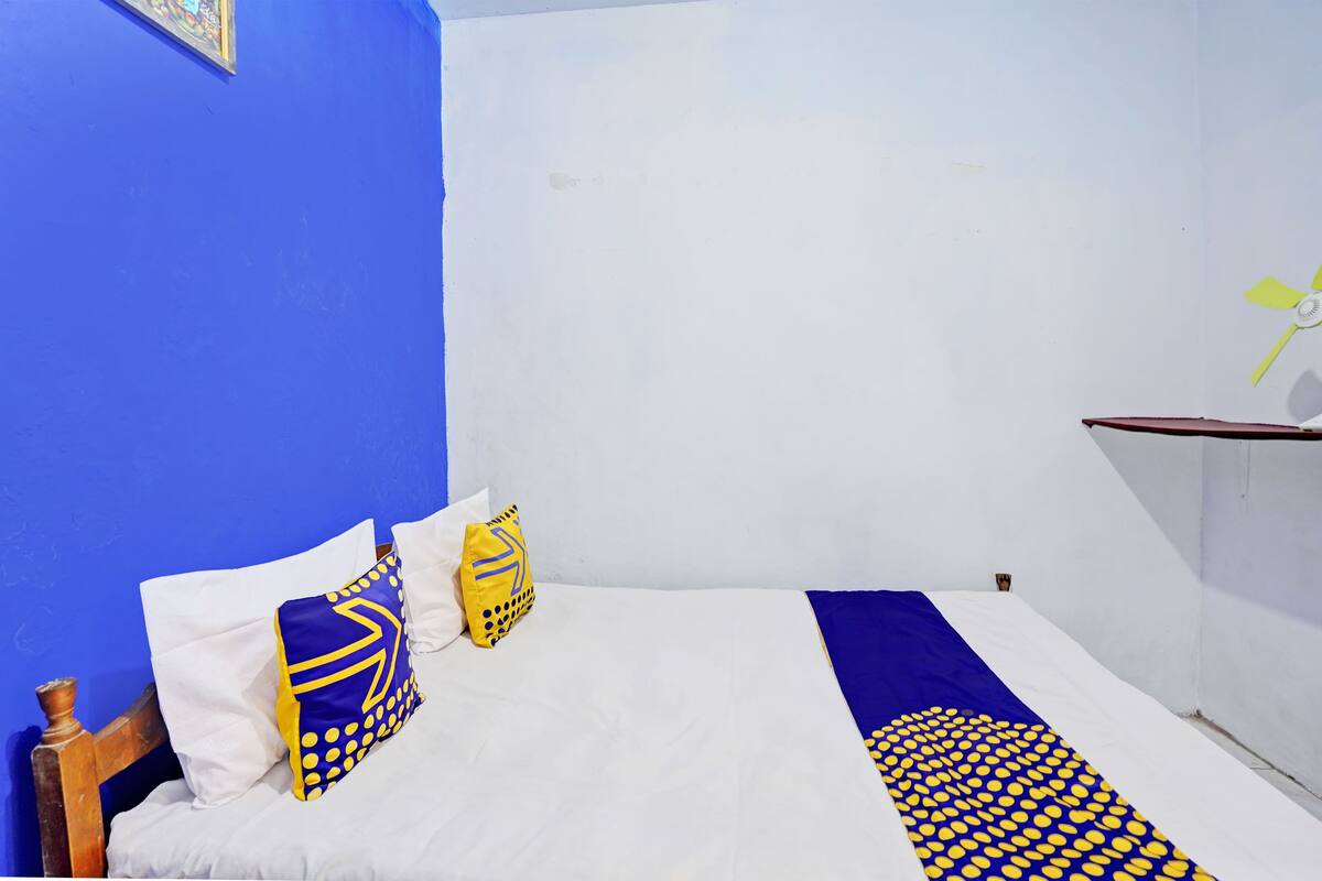 Una habitación con cama, paredes azules y un ventilador de techo.