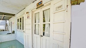 Un couloir aux portes et fenêtres blanches, une enseigne au-dessus des portes et un sol carrelé.