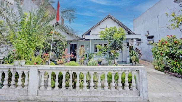 Un bâtiment doté d’un balcon, entouré d’une végétation luxuriante et surplombant un ciel dégagé.
