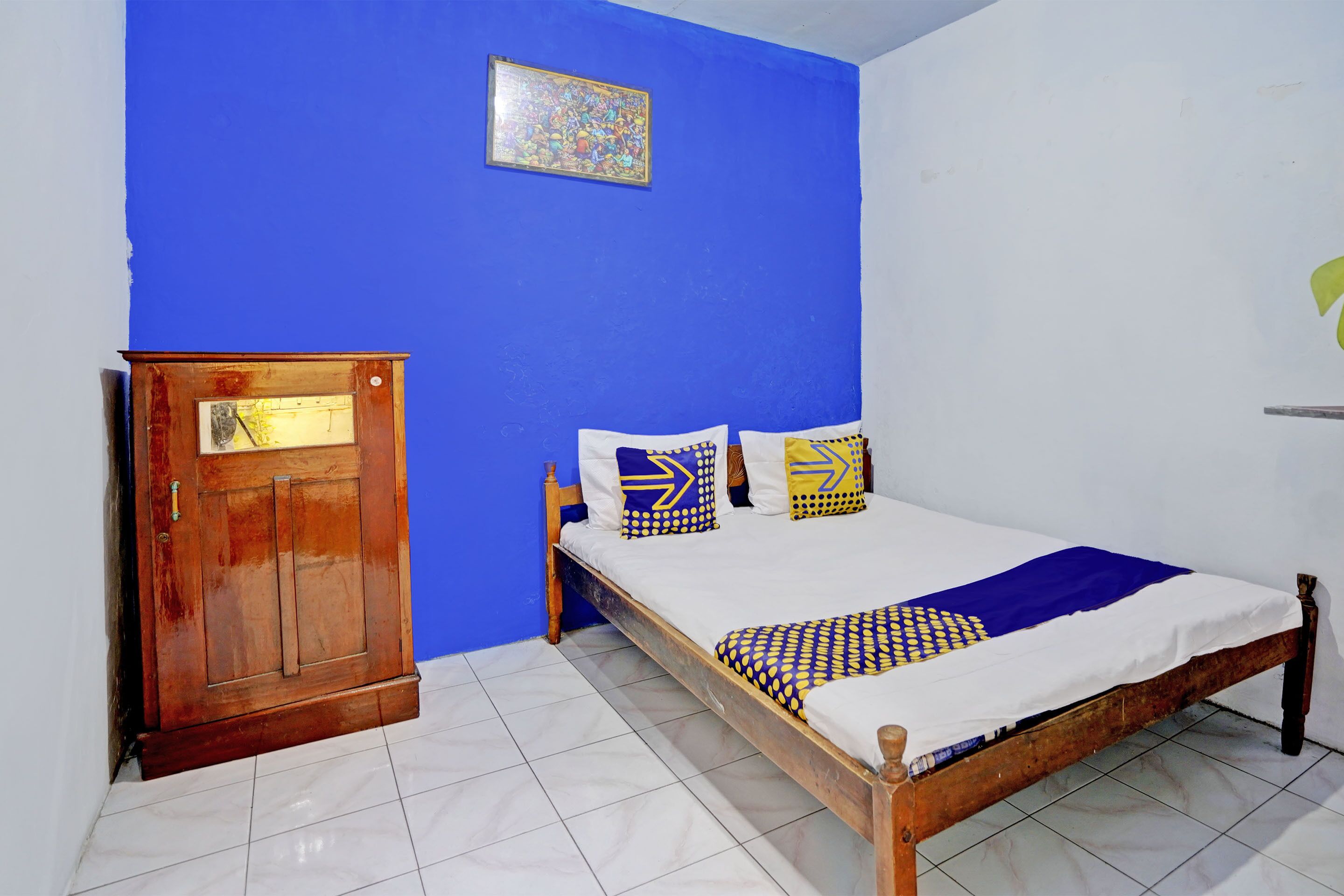 A room with a bed, a wooden wardrobe, and a blue wall.