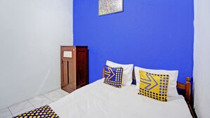 Une chambre avec un mur bleu, une armoire en bois et deux lits dotés d’oreillers à motifs.