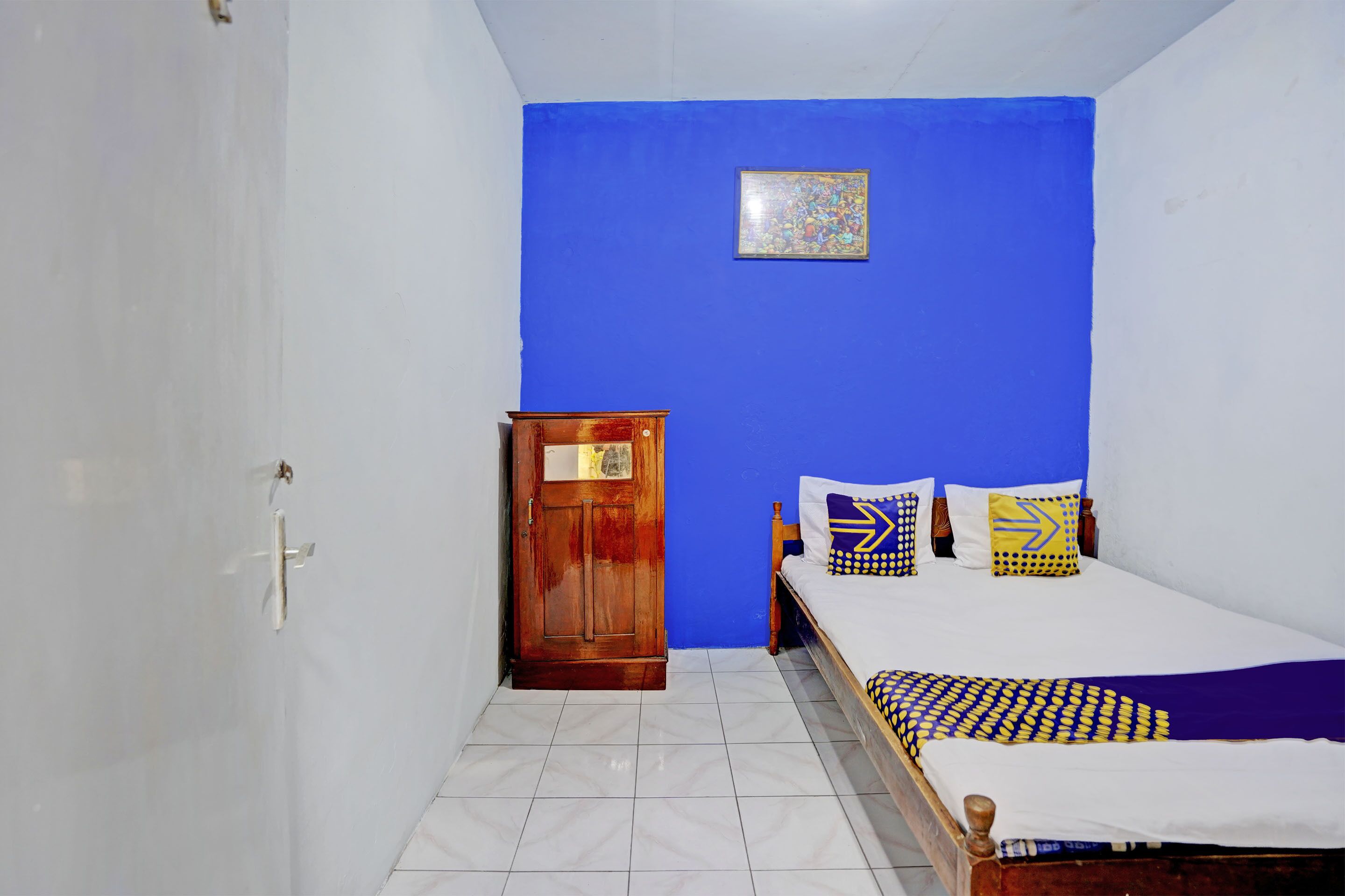A room with a bed, a wooden wardrobe, and a blue wall.