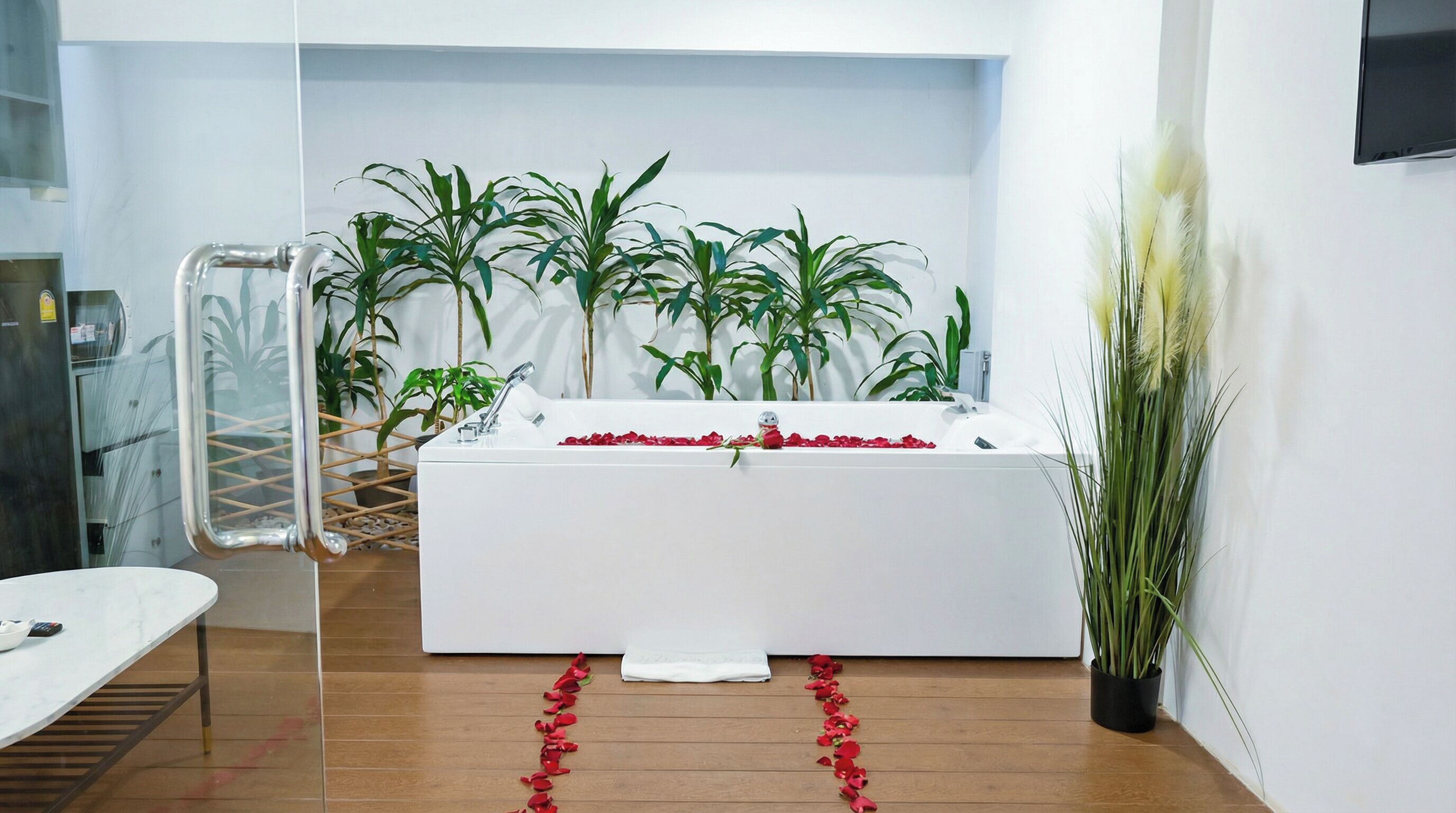 Un baño moderno con una bañera blanca, plantas verdes y suelo de madera.