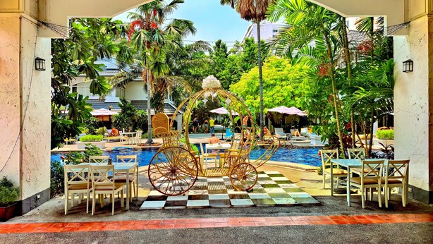 A pool area with a checkered floor, seating, and a decorative carriage. - Pooh Beach Resort & Spa (Pattaya)