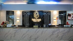 A reception desk with a sign reading 'Poon Beach Resort & Spa,' a marble counter, and a decorative wall with a sky mural. - Pooh Beach Resort & Spa (Pattaya)