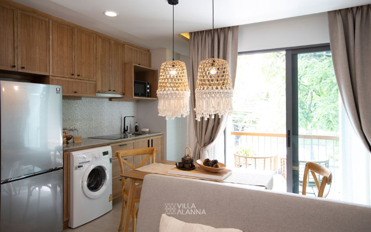 A compact kitchen with wooden cabinets, a washing machine, and a dining area with a table and chairs.