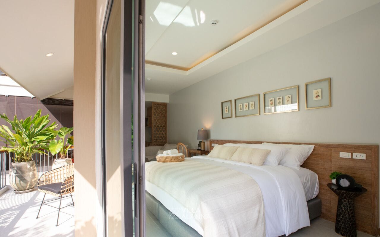 A bedroom with a large bed, a bedside table, a lamp, and framed pictures on the wall.