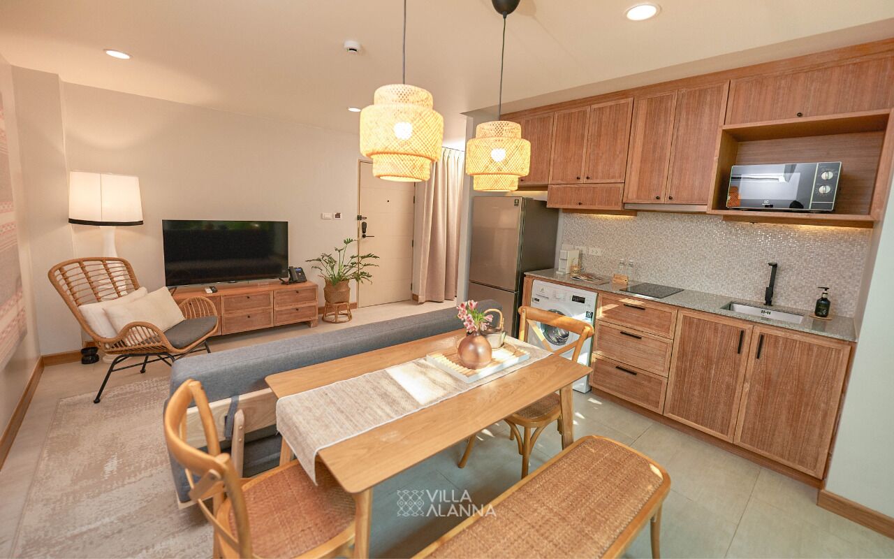 Una cocina moderna con armarios de madera, microondas integrado y una zona de comedor con mesa y sillas.