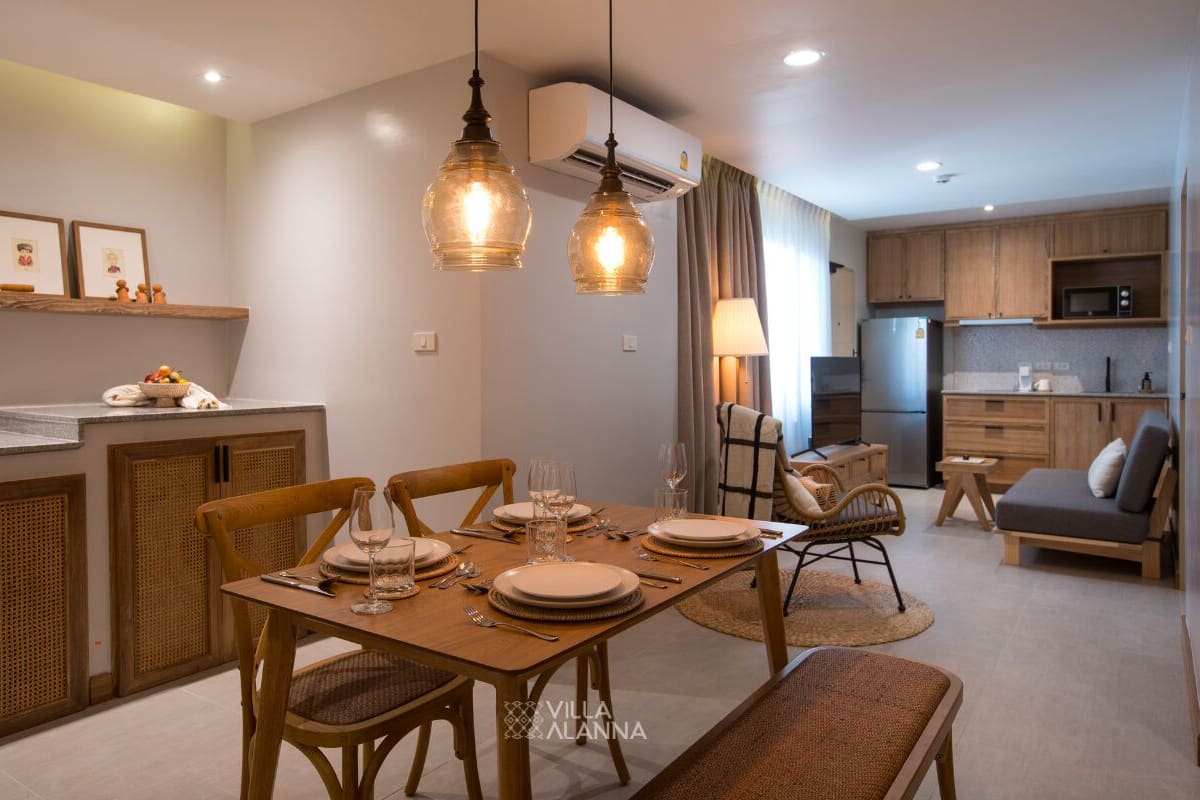 Una cocina moderna con armarios de madera, microondas integrado y un comedor con mesa y sillas de madera.