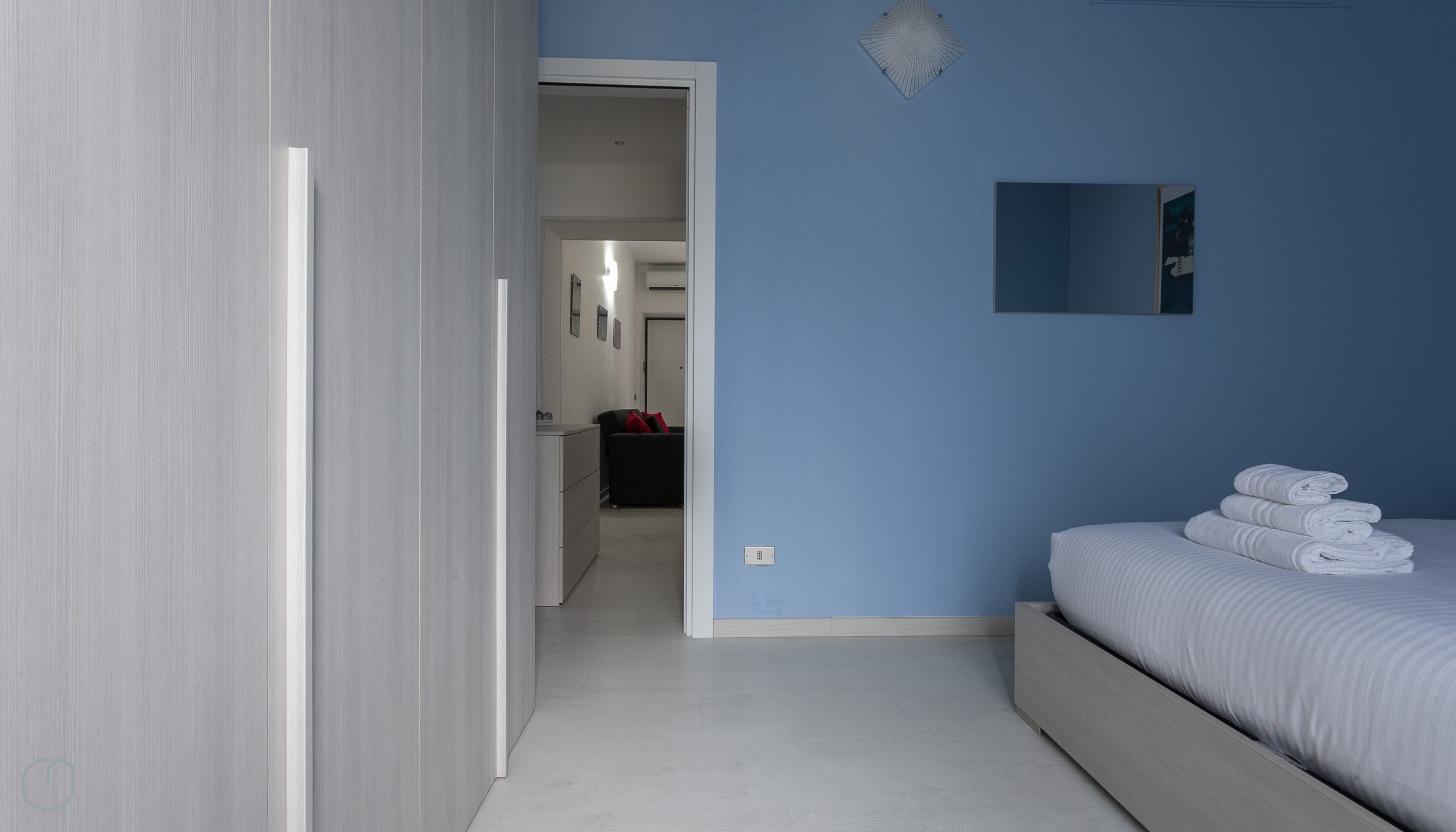 Une chambre à coucher avec un lit, une commode et un miroir au mur.