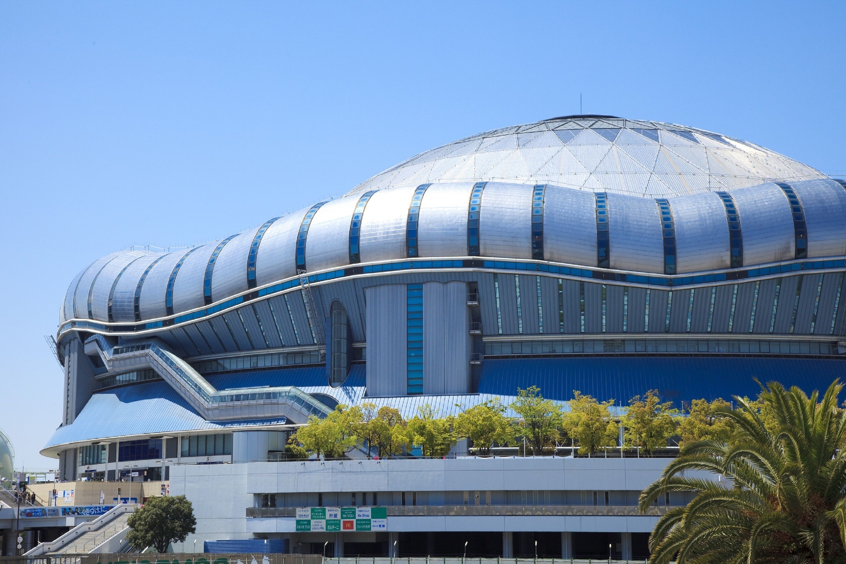 A modern stadium with a large, curved roof and multiple levels.