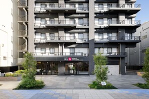 A multi-story hotel with a modern design, featuring balconies on each floor, a central entrance, and a sign indicating it is the Osaka-Shinseikai Hotel. - The Onefive Osaka Shinsekai (Osaka)
