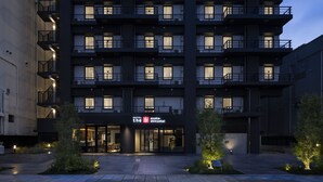 A multi-story hotel with a modern design, featuring balconies on each floor, a well-lit entrance, and a sign indicating the hotel name. - The Onefive Osaka Shinsekai (Osaka)