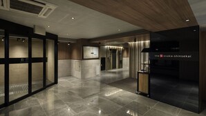 A modern hotel lobby with a polished tile floor, wooden accents, and a reception area with a digital display. - The Onefive Osaka Shinsekai (Osaka)