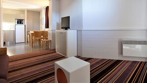 A modern hotel room with a kitchenette, a dining area, and a TV on a cabinet. - 2-room apartment with balcony and ski-in/ski-out access, 5 people (Avoriaz)